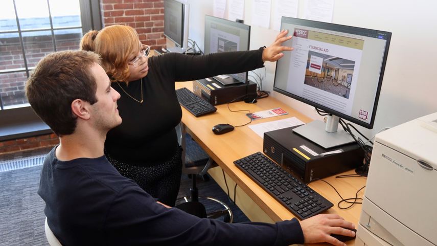 Student Financial Services staff directing student using computer