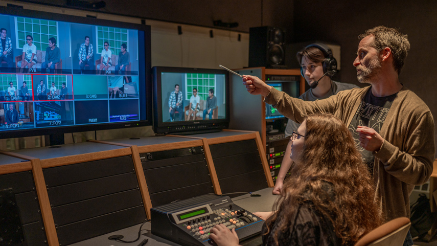 professor teaching video production techniques at switchboard and monitors